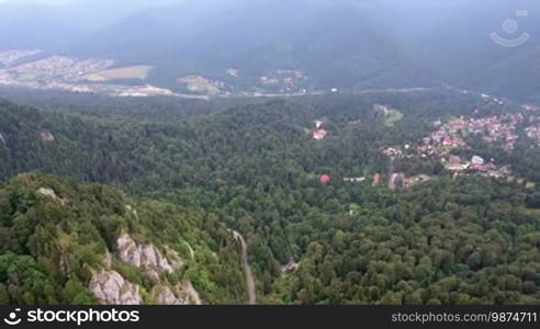 Aerial view of Romania mountains landscape town valley scenery in summer day. 4K aerial motion over forest and trees.