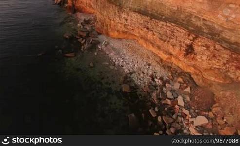 Aerial view of the precipice with terrible rocks by the sea at sunset.