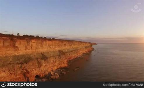 Aerial view of the precipice with terrible rocks by the sea at sunset
