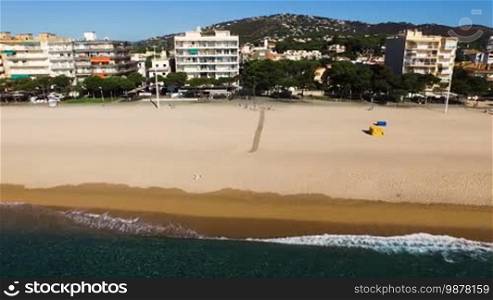 Aerial view of yellow sandy beach with people on the coast. Spain, Catalonia