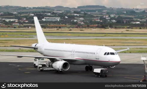 Airplane being prepared for a flight with workers and cars around