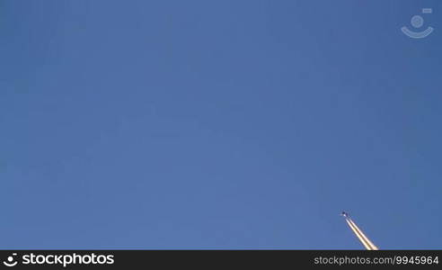 Airplane flies overhead on clear, blue sky