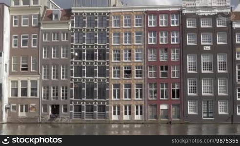 AMSTERDAM, NETHERLANDS - AUGUST 9, 2016: View of old European typical district with buildings in the city center on the river. Amsterdam is home to more than one hundred kilometers (60 miles) of canals