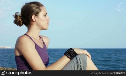 Attractive young Caucasian woman looking at the ocean and smiling at the camera. Copy space