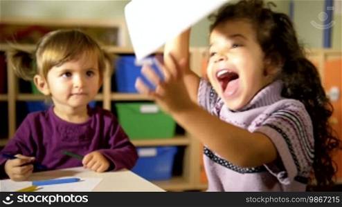 Babies having fun at school, two happy little girls drawing with colors and crayons in kindergarten. Sequence