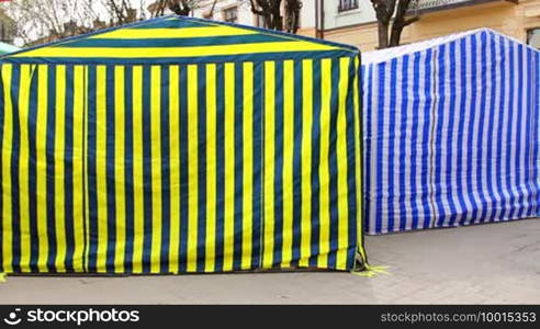 Back side of two trade tents at city, their walls are waving in breeze