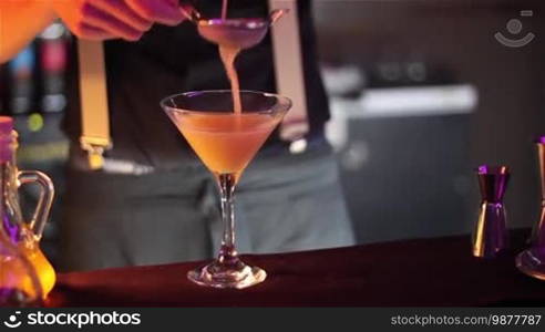 Bartender, barman is making delicious cocktail at bar counter using ice and sweet liquor, and making tricks, shots