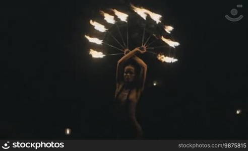 Beautiful woman doing fire show at the beach at night - video in slow motion