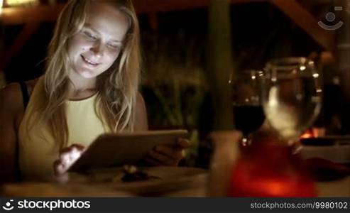 Beautiful woman using tablet PC in luxurious restaurant on tropical resort