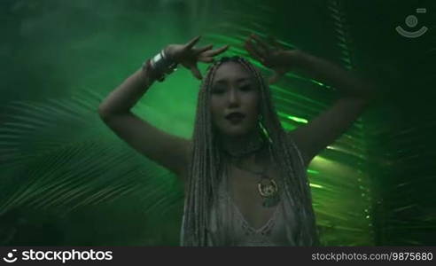 Beautiful woman with braids dancing near the palm tree in the jungle