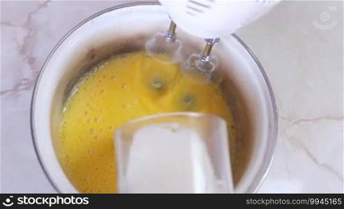 Blending egg yolks and sugar with the help of a modern mixer, close-up