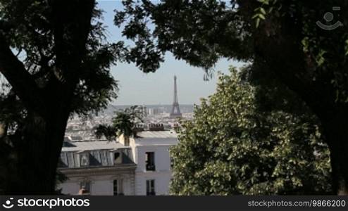 Blick auf Stadt und Eiffelturm in Paris, umrahmt von Bäumen.