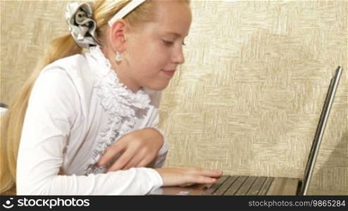 Blonde little girl using laptop at home