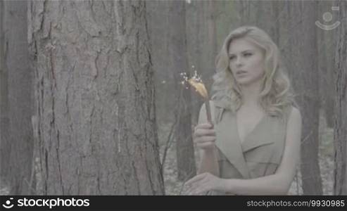 Blonde woman in the forest holding a fire fountain