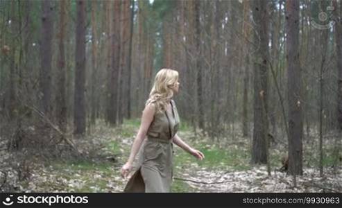 Blonde woman in the forest looking from behind the tree