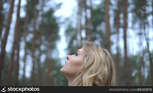 Blonde woman in the forest looking up