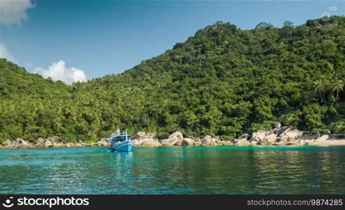 Blue boat in the bay with forest background