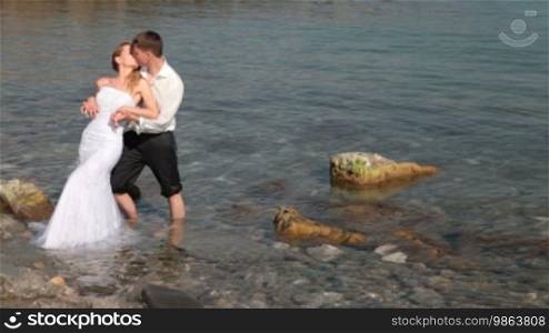 Bride and groom hugging at beach