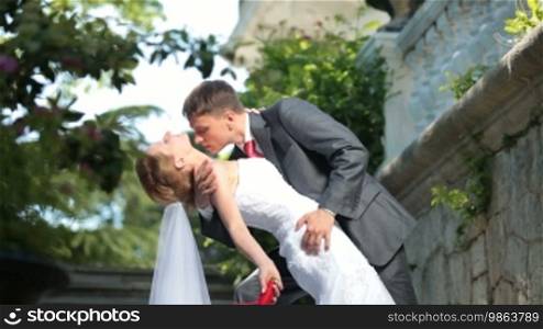 Bride and groom kissing in park