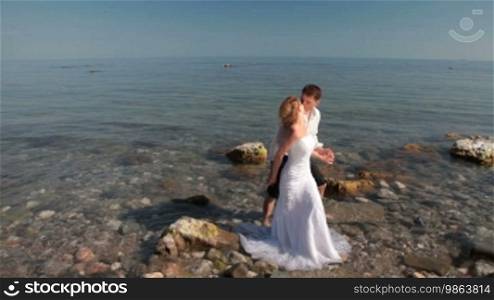 Bride and groom kissing in the water at the beach