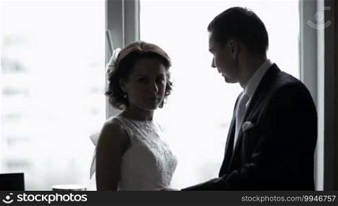 Bride and groom looking out the window. Romantic moments.