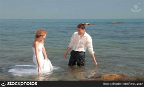 Bride and groom splash in the water at the sea
