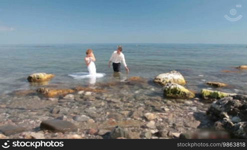 Bride and groom splash in the water at the sea