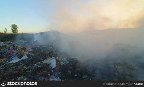 Burning garbage toxic smoke rises into the air pan shot