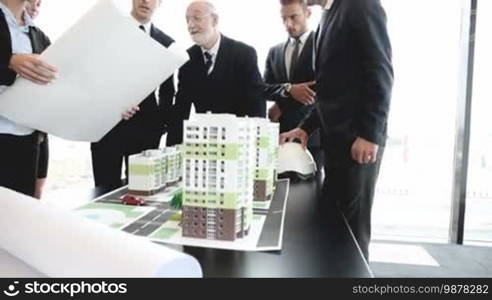 Business meeting of architects and investors looking at model of residential quarter houses