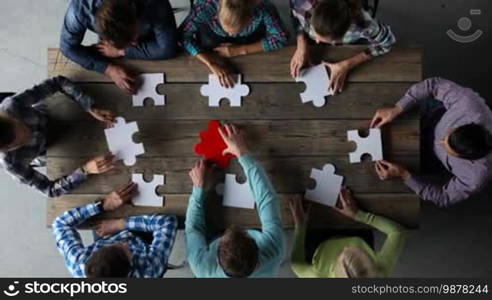 Business people and puzzle on wooden table, teamwork concept