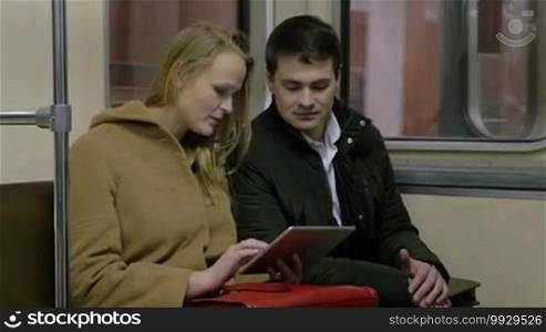 Business people are working using a tablet PC while riding a metro.