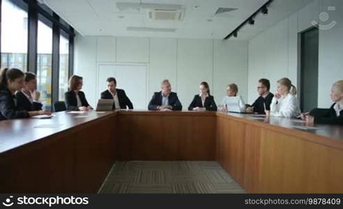 Business people at corporate meeting sitting around table and talking