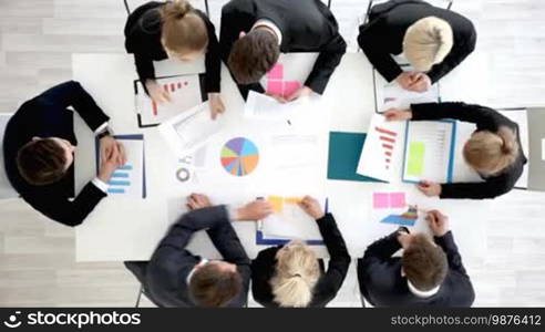 Business people work with statistics documents with tables and diagrams sitting around the table