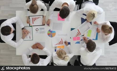 Business people work with statistics documents with tables and diagrams sitting around the table