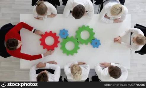 Business problem solution, mechanism of business, teamwork concept, business team sitting around white table with cogs