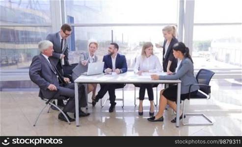 Business team sitting by the table with laptop and documents in office