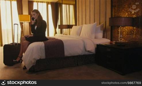 Business travel, people traveling, working in hotel room, manager. Caucasian businesswoman, girl, woman at work, talking on cell phone, mobile telephone. Career and success.