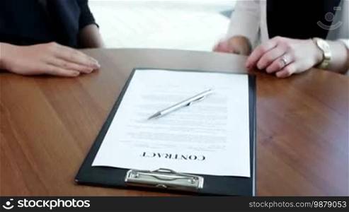 Business women signing contract at meeting, close-up view