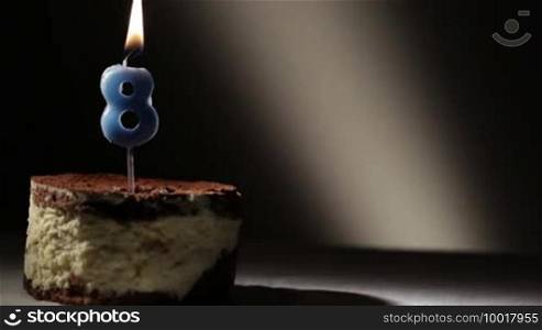 Candle eight in tiramisu cake. Birthday vintage background.