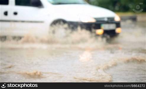 Car driving through big puddle on urban road