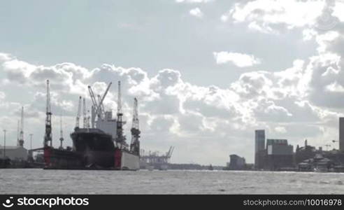 Cargo ship in Hamburg port. Bright backlit clouds.