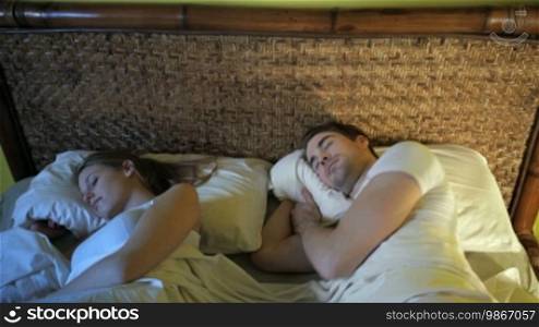 Caucasian heterosexual couple in bed, man suffering from insomnia. Crane shot