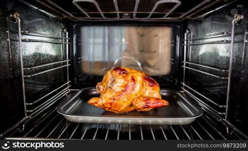 Chef prepares roast chicken (focus on chicken) in the oven, view from the inside of the oven. Cooking in the oven.