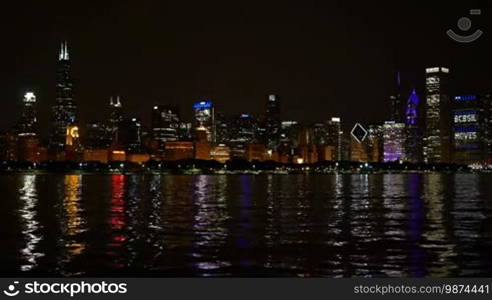 Chicago downtown cityscape reflected on the Michigan lake at nighttime. Awesome Chicago financial city center skyline at night. Colorful illuminated skyscrapers of Chicago.