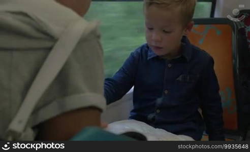 Child and mother traveling by train. They checking trip route with map