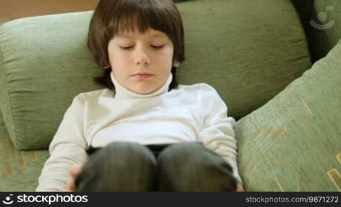 Child playing computer games on tablet PC at home