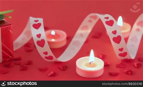 Chocolate cupcake against a red background with roses and gift at candlelight for a bright, fun and cheerful Valentine's Day. Love and romance concept.