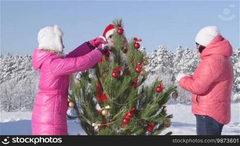 Christmas holidays recreational activity in winter forest family decorating Christmas tree