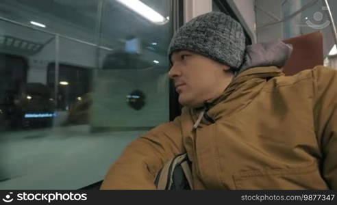 Cinemagraph - Man commuter traveling by train in winter evening. He looking at the station, unidentified passengers reflecting in the window