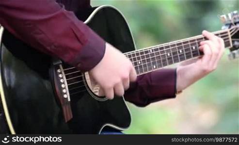 Close up of a person's hands playing acoustic guitar, artist musician outdoors.